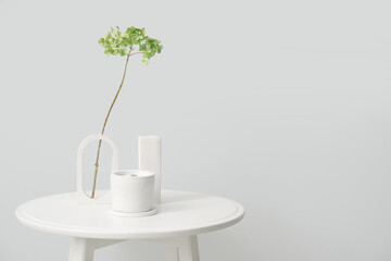 Hydrangea flowers and candle on table near light wall in room