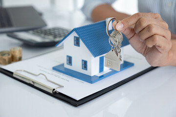 Real estate agent holding a key and asking costumer for contract to buy, get insurance or loan real estate or property.