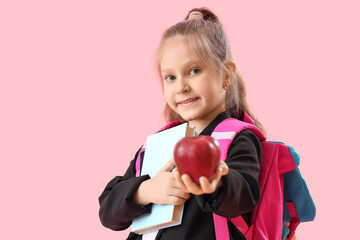 Little schoolgirl with book and apple on pink background