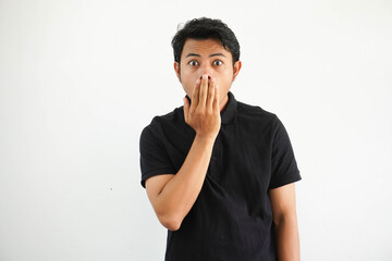 Fototapeta na wymiar young asian man close his mouth with hands and showing shocked expression wearing black polo t shirt isolated on white background