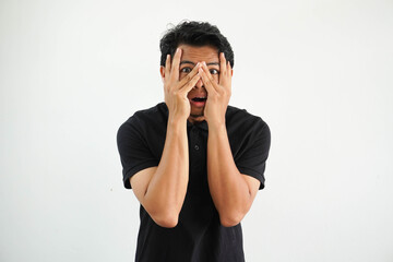 Young asian man isolated on white background blink through fingers frightened and nervous, wearing...