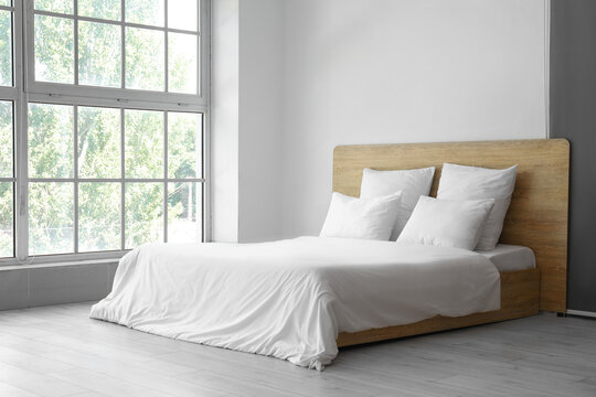 Interior of light bedroom with comfortable double bed and white pillows