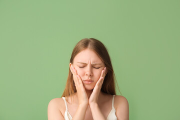 Young woman suffering from toothache on green background