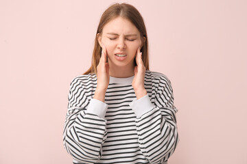 Young woman suffering from toothache on pink background