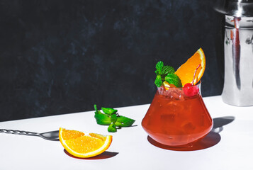 Red fruit cocktail drink with rum, pineapple juice, orange, mint, cocktail cherry and ice. Gray and...