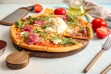 Wooden board of tasty pizza with Burrata cheese on blue background