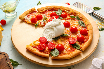 Wooden board of tasty pizza with Burrata cheese on blue background