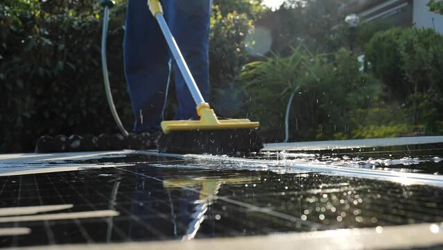 Cleaning solar panels from dust and dirt.Man washing solar panels with water close-up.Solar Panel Efficiency.solar power technology.renewable energy.Alternative natural energy sources. 4k footage