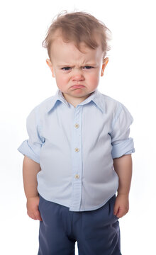 A cute but very angry little baby boy child wearing blue shirt and trousers, isolated on white background