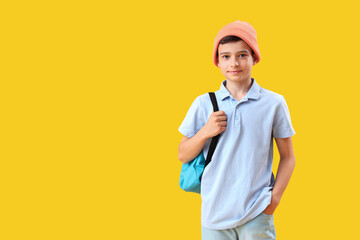 Portrait of schoolboy with backpack on orange background