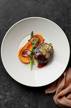 Slow-cooked beef cheek, charred shallots, asparagus spears, romesco, pancetta herb crumbs