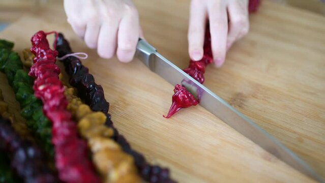 Close-up view of female hands cutting Georgian churchkhela candy into pieces