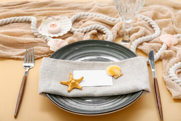 Beautiful table serving with marine decor and blank invitation card on beige background