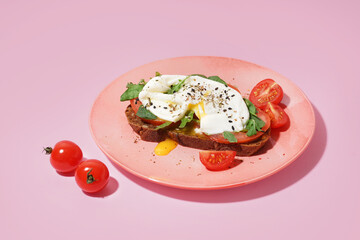 Plate of tasty sandwich with egg on pink background