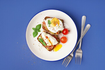 Plate of tasty sandwiches with egg on blue background