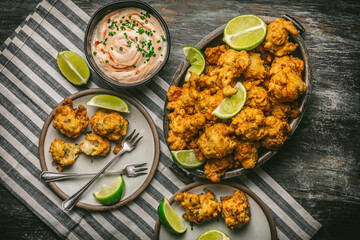 Shrimp Fritters in basket and plate with dipping sauce and limes