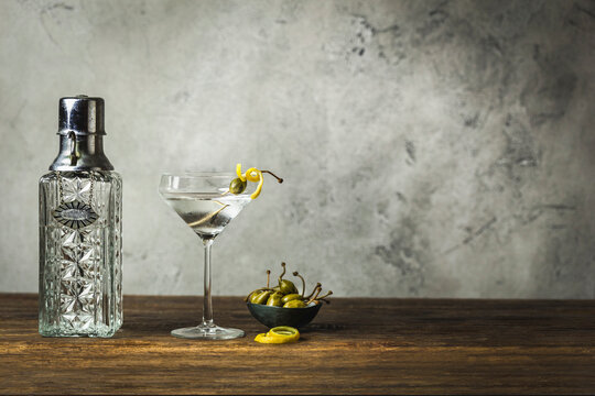 Martini with lemon twist and caperberry, vintage decanter, caperberries in small bowl