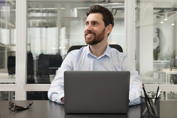 Man working on laptop at black desk in office