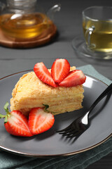 Piece of delicious Napoleon cake with strawberries on table