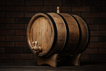 Wooden barrel with tap on table near brick wall