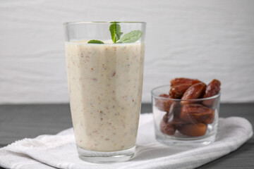 Glass of delicious date smoothie with mint and dried fruits on grey table, closeup. Space for text