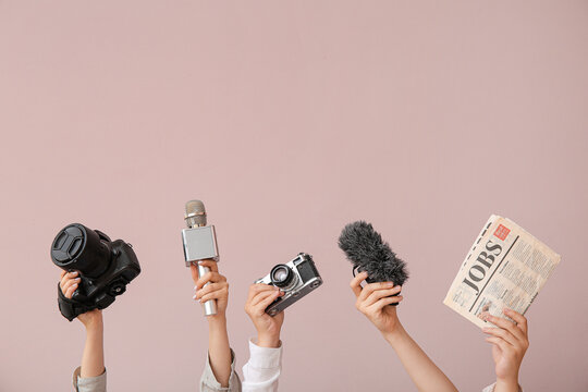 Female hands with newspaper, microphones and photo cameras on color background