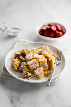 A plate of torn french toast pancakes with a side of strawberry compote