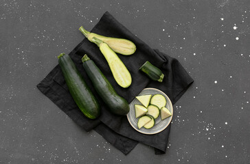Fresh green zucchini and plate with slices on black background