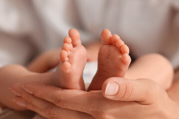 Obraz na płótnie Canvas Mother holding her newborn baby, closeup view on feet. Lovely family