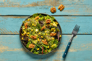 Plate with fresh salad on blue wooden background