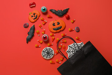 Shopping bag with tasty candy corns and cookies for Halloween on red background