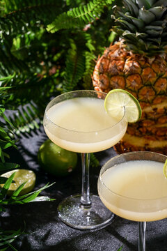 Summer cocktail pineapple daiquiri with vodka, pineapple juice, frozen motion and flying drops. Tropical background with palm leaves