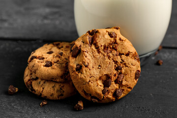 Tasty cookies with chocolate chips on black wooden background