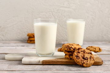 Glasses of milk and tasty cookies with chocolate chips on table