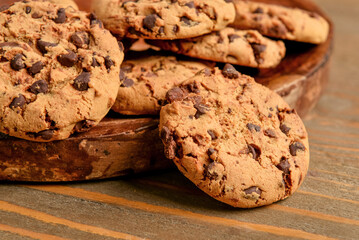Plate of tasty cookies with chocolate chips on wooden background