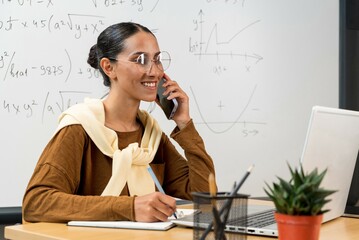 Female Mixed Race professor having break with online class and talking on mobile phone . Smiling...