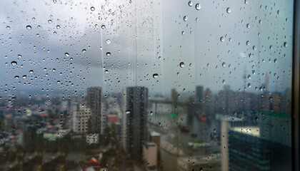 a shot from highrise building through wet window plane with raindrop moment seeing downtown area during rain storm.