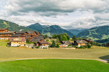 Fototapeta na wymiar swiss countryside with green fields, houses and Alp mountains in the background, Switzerland