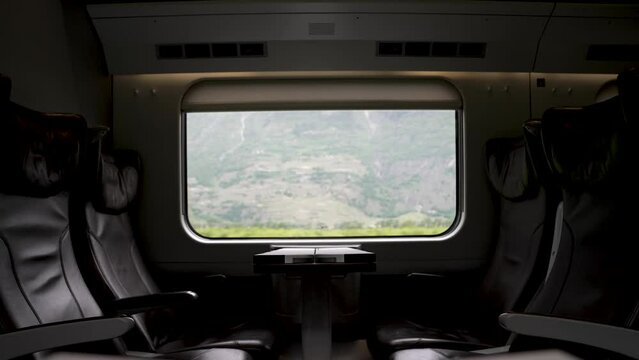 An empty business class train carriage with a scenic view of the Swiss countryside passing by through the window, Switzerland