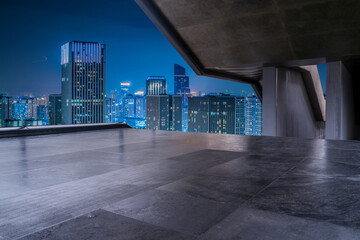 empty concrete floor with modern cityscape in downtown at night.