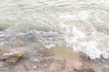 Obraz premium Water splashes from wave bumping against rocky shore brown. which is important tourist destination. Background image is sea blue of bright sunlight make picture very bright. Beach at Penang Malaysia.
