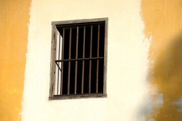 Fototapeta na wymiar wooden window on cement stone wall painted yellow