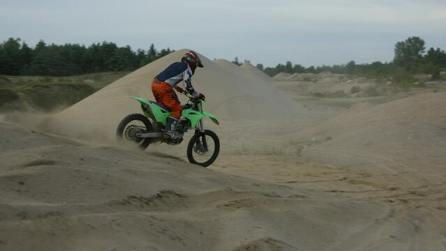 Dirt biker jumps sand dunes and does no hander trick