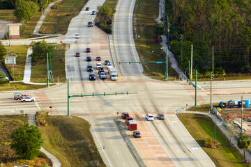 View from above of wide multilane road with driving vehicles at intersection with traffic lights....