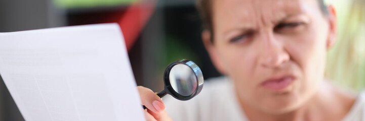 Fototapeta premium Woman using magnifying glass to read text on paper, eye diseases and health problem concept.