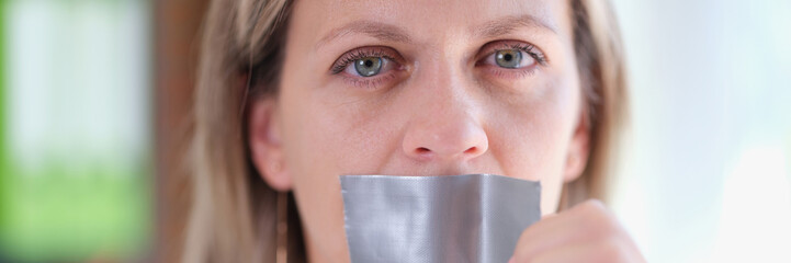 Woman removes adhesive tape from her mouth close up.