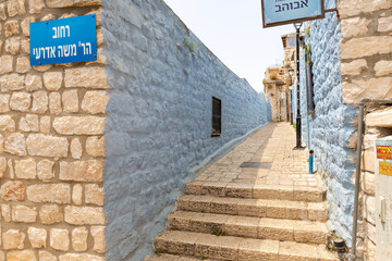 Quiet street with a stone pavement and stone walls of houses in the old part of Safed city in...