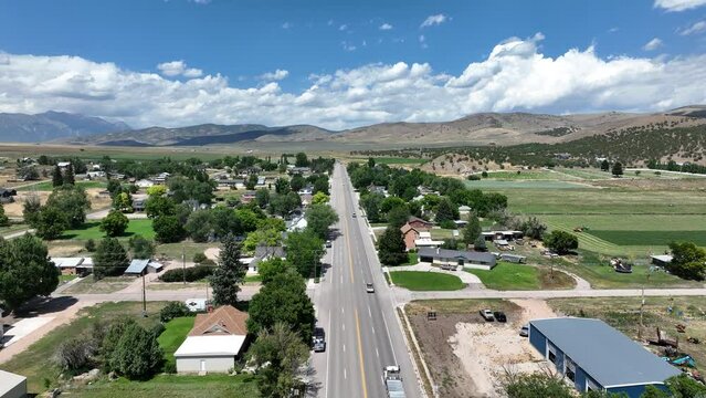Aerial rural town main street dump truck summer Utah pull. Farming community agricultural economy. Spring summer weather mountain valley green agriculture field. Homes, barns and buildings.
