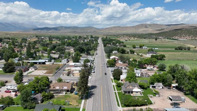 Aerial timelapse rural city main street Utah. Farming community agricultural economy. Spring summer weather mountain valley green agriculture field. Homes, barns and buildings.