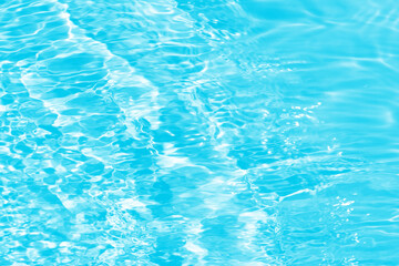 Blue water with ripples on the surface. Defocus blurred transparent blue colored clear calm water surface texture with splashes and bubbles. Water waves with shining pattern texture background.